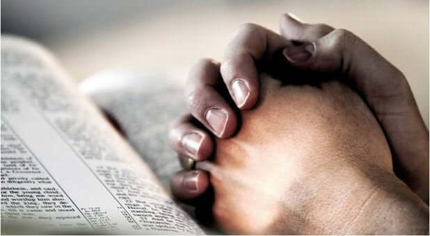 Praying hands on a Bible