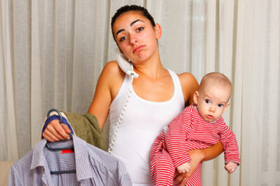 mom holding baby and ironing