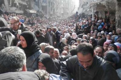 Syrian refugees wait in line in Damascus for bags of food.