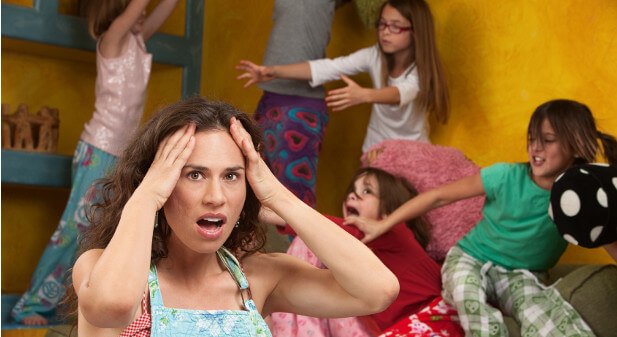 mom with kids jumping on the bed behind her