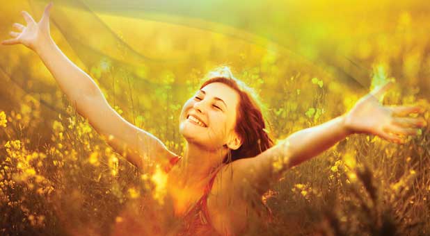 woman praising God in field of flowers