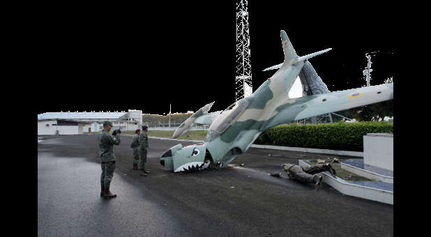 Military officers stand next to sculpture damaged by Ecuadorian quake.