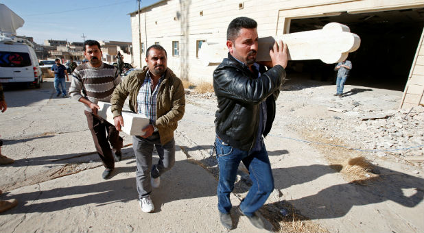 Iraqi Christians carry parts of a new cross, which will be erected over the Mar Korkeis church, after the original cross was destroyed by Islamic State militants, during a procession in the town of Bashiqa, Iraq