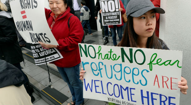 People hold protest signs during Friday prayers to show solidarity with the Muslim community at the Islamic Center