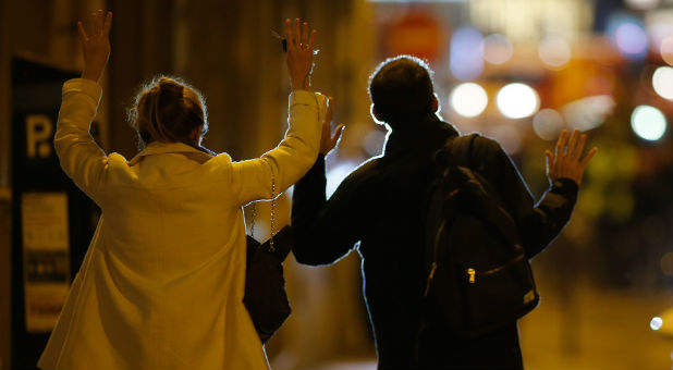 People raise their arms to show their hands as they walk toward police on a side road near the Champs Elysees Avenue after two policemen were killed and another wounded in a shooting incident in Paris, France, April 20, 2017.