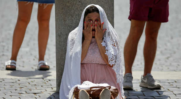 A faithful shelters from the sun before the start of the Angelus prayer led by Pope Francis in Saint Peter's Square at the Vatican.