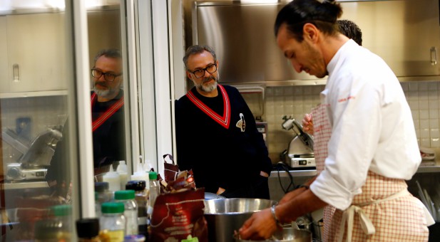 Michelin-starred chef Massimo Bottura looks at a staff member working at Refettorio Ambrosiano in Milan, Italy.