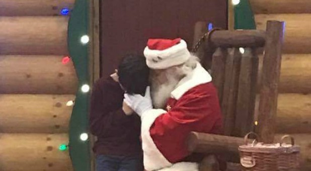 A little boy prays with Santa.