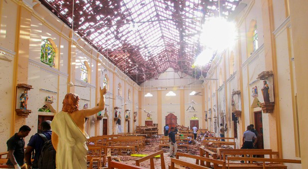 A blood-spattered statue of Jesus Christ is pictured while crime scene officials inspect the site of a bomb blast.