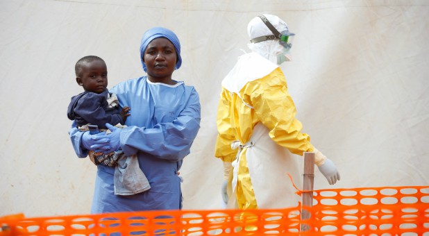 Mwamini Kahindo, an Ebola survivor working as a caregiver to babies who are confirmed Ebola cases, holds an infant.