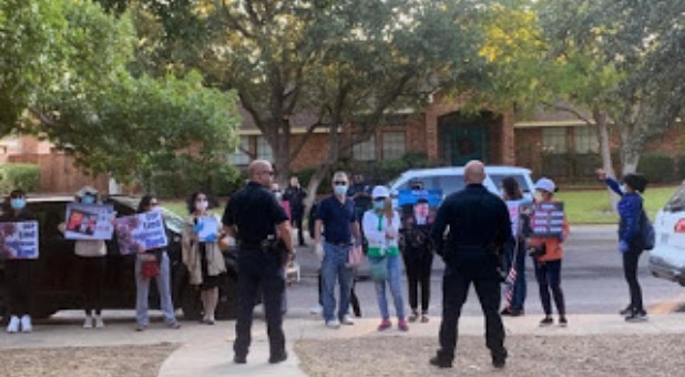 Police officers protect Bob Fu's property from protesters.