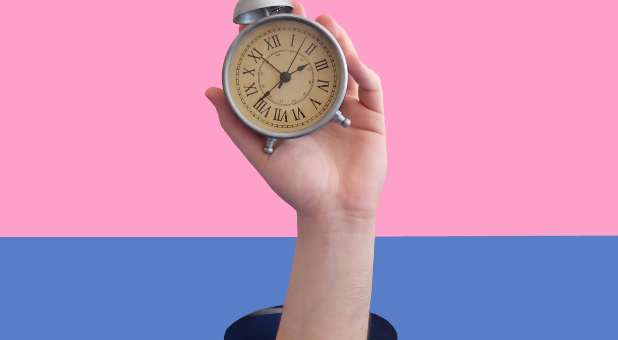 hand coming out of a hole, holding old-fashioned alarm clock